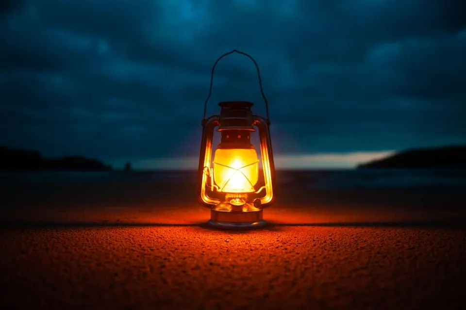 Lantern glowing on a beach at dusk