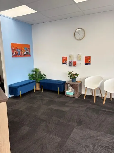 Bright waiting room at Ocean Breeze Health with blue seating and plants